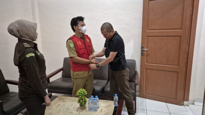 
					Penyidik Tipidsus Kejaksaan Negeri Luwu Timur memborgol tangan Kepala Desa Balai Kembang , Aswan Musa (rompi merah), Selasa malam, (22/07/25)